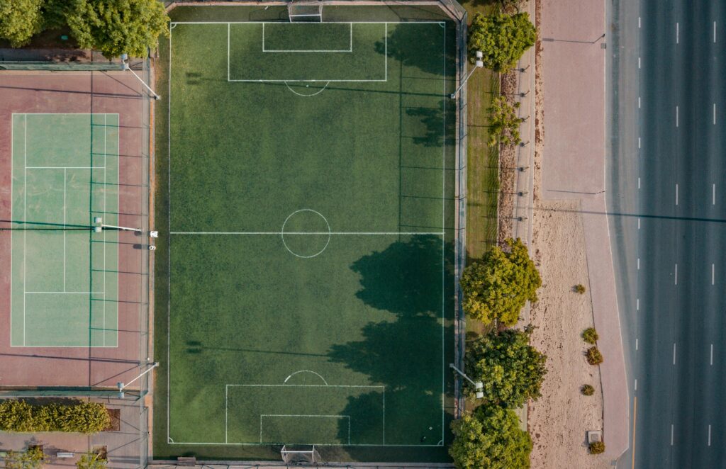 An aerial shot of a football and tennis court in Dubai, surrounded by trees.